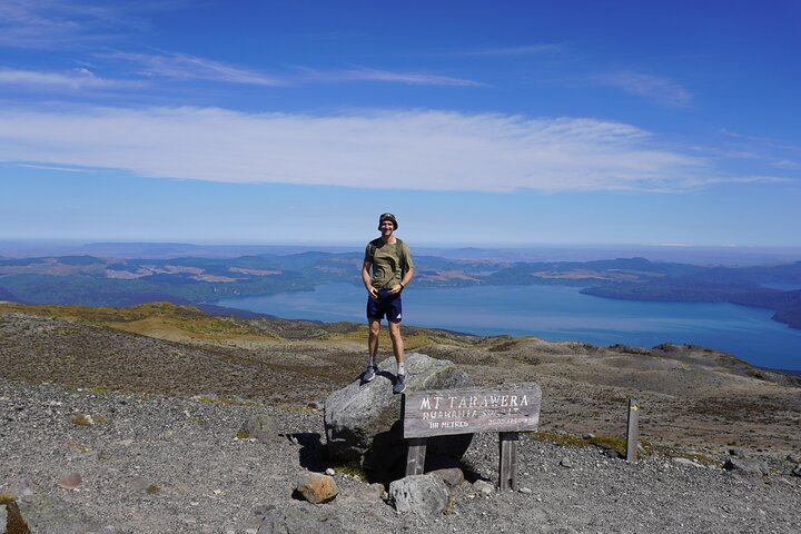 A panoramic view of Rotorua’s stunning geothermal landscape unfolds as adventurous hikers reach the iconic Mt. Tarawera's summit a testament to nature's raw beauty and rich history.